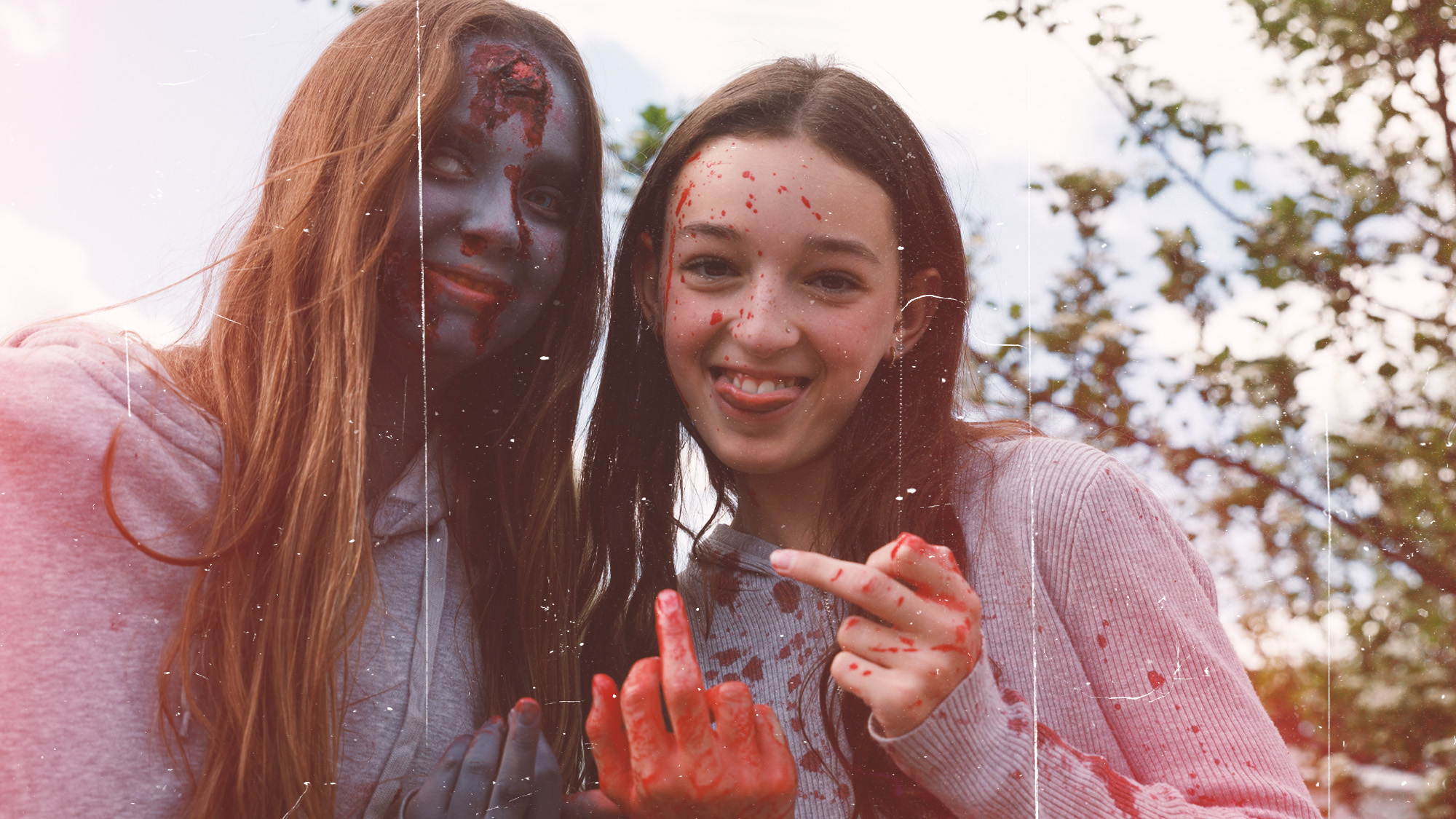 Two cast members covered in blood, flipping off camera